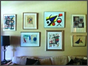 A collection of works by famous artists hung above sofa in living area.